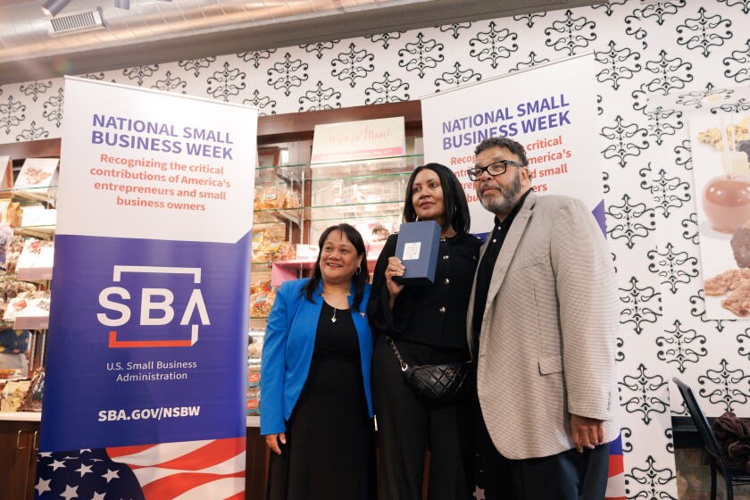 Left to Right: US Small Business Administration Regional Administrator Geri Aglipay, Kilwins Owner Jackie Jackson and Illinois Assistant District Manager Mark Ferguson at Kilwins' Andersonville booth with a "National Small Business Week" sign in store